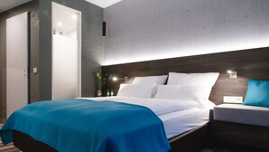Een moderne hotelkamer met een groot bed, een nachtkastje en een wandlamp.