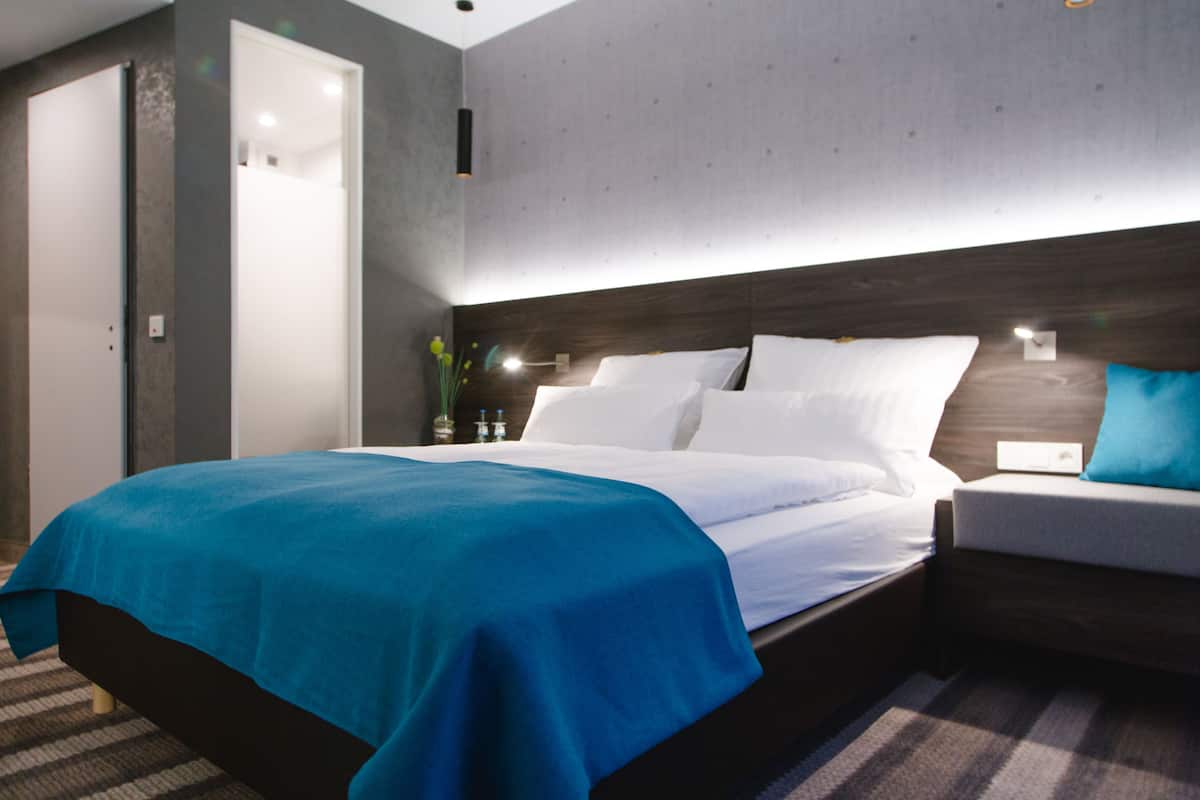 Een moderne hotelkamer met een groot bed, een nachtkastje en een wandlamp.