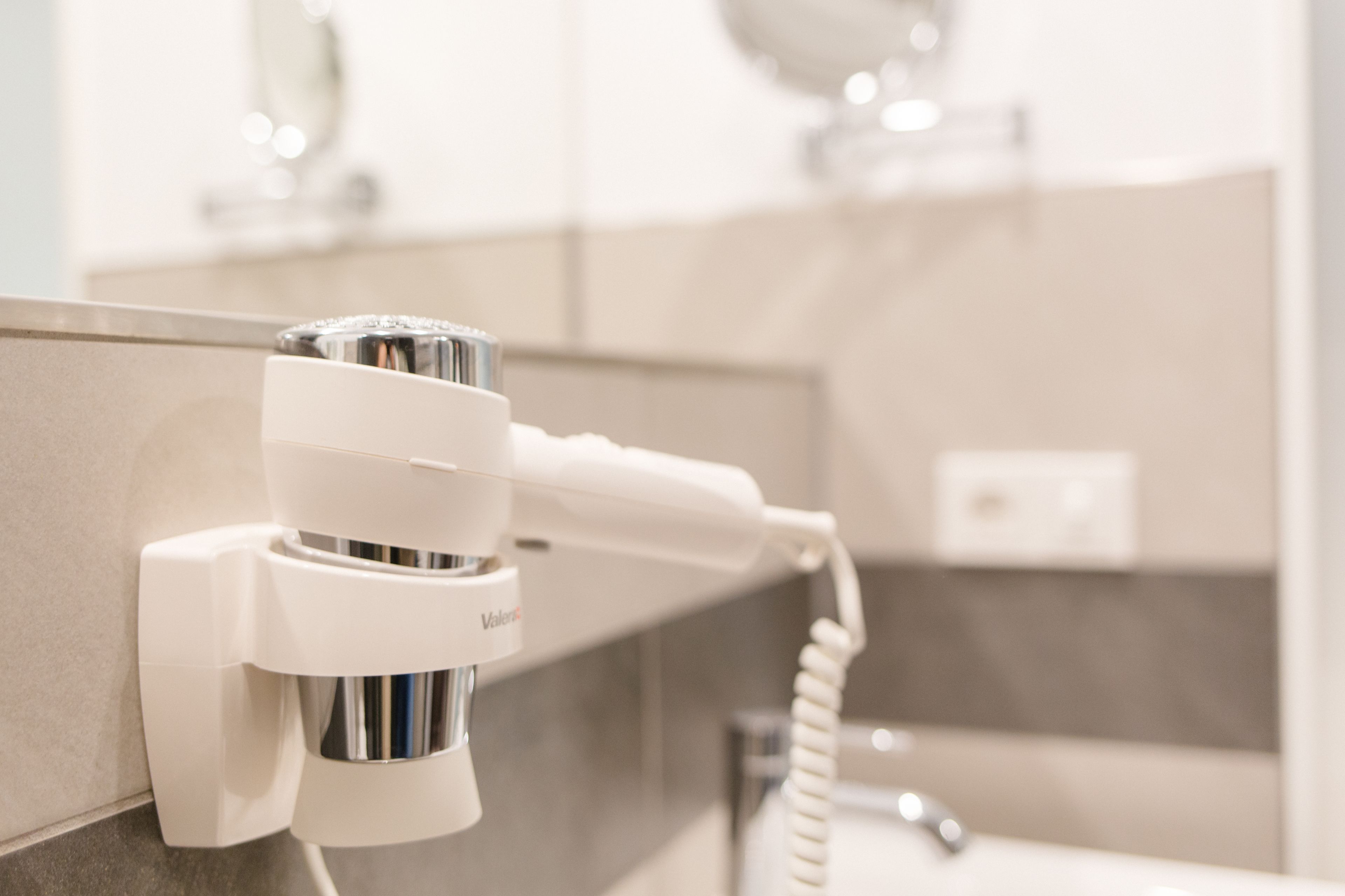 Een haardroger bevestigd aan een muur in een badkamer.