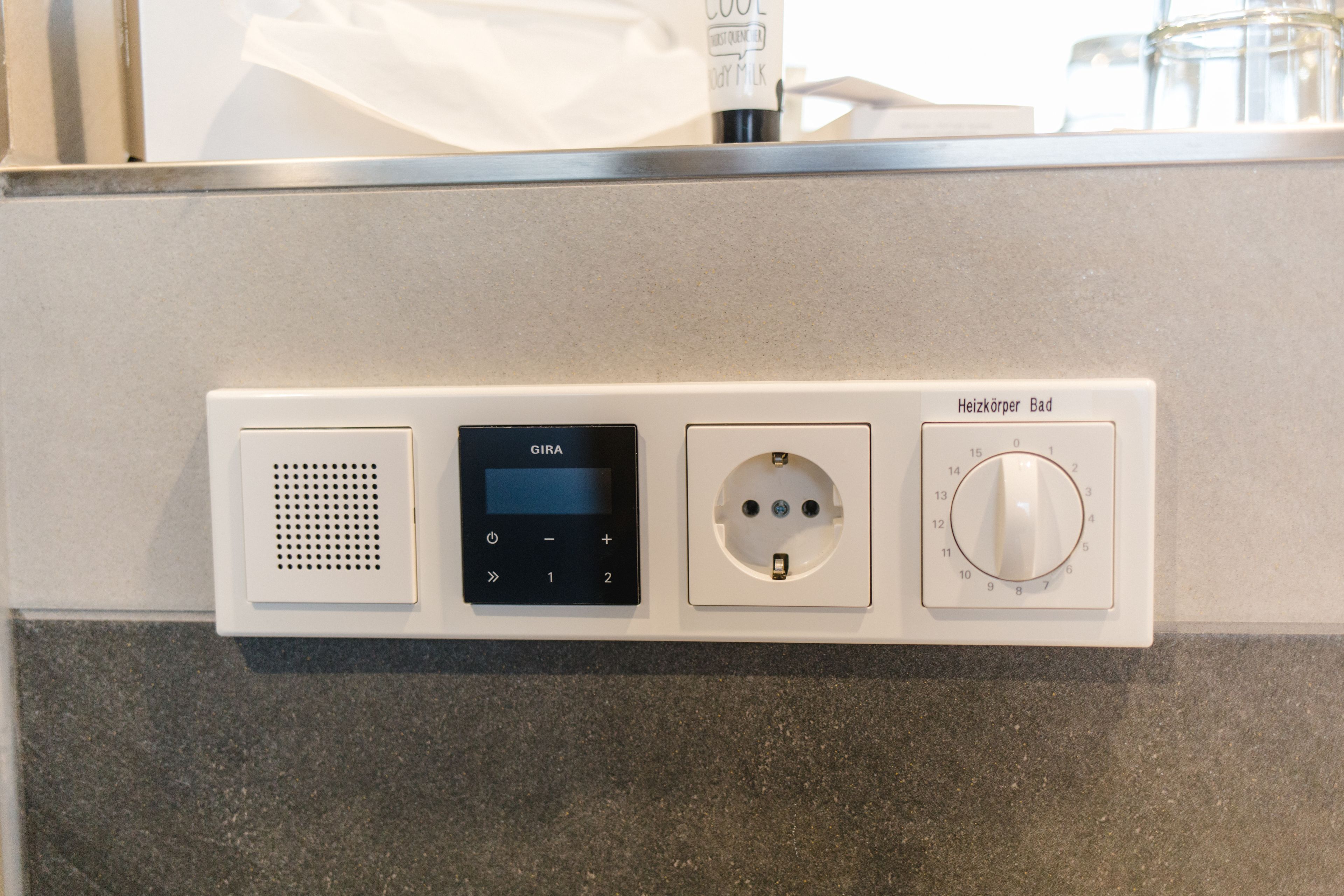 A control panel with a GIRA device, a socket, and a Heizkörper Bad knob.