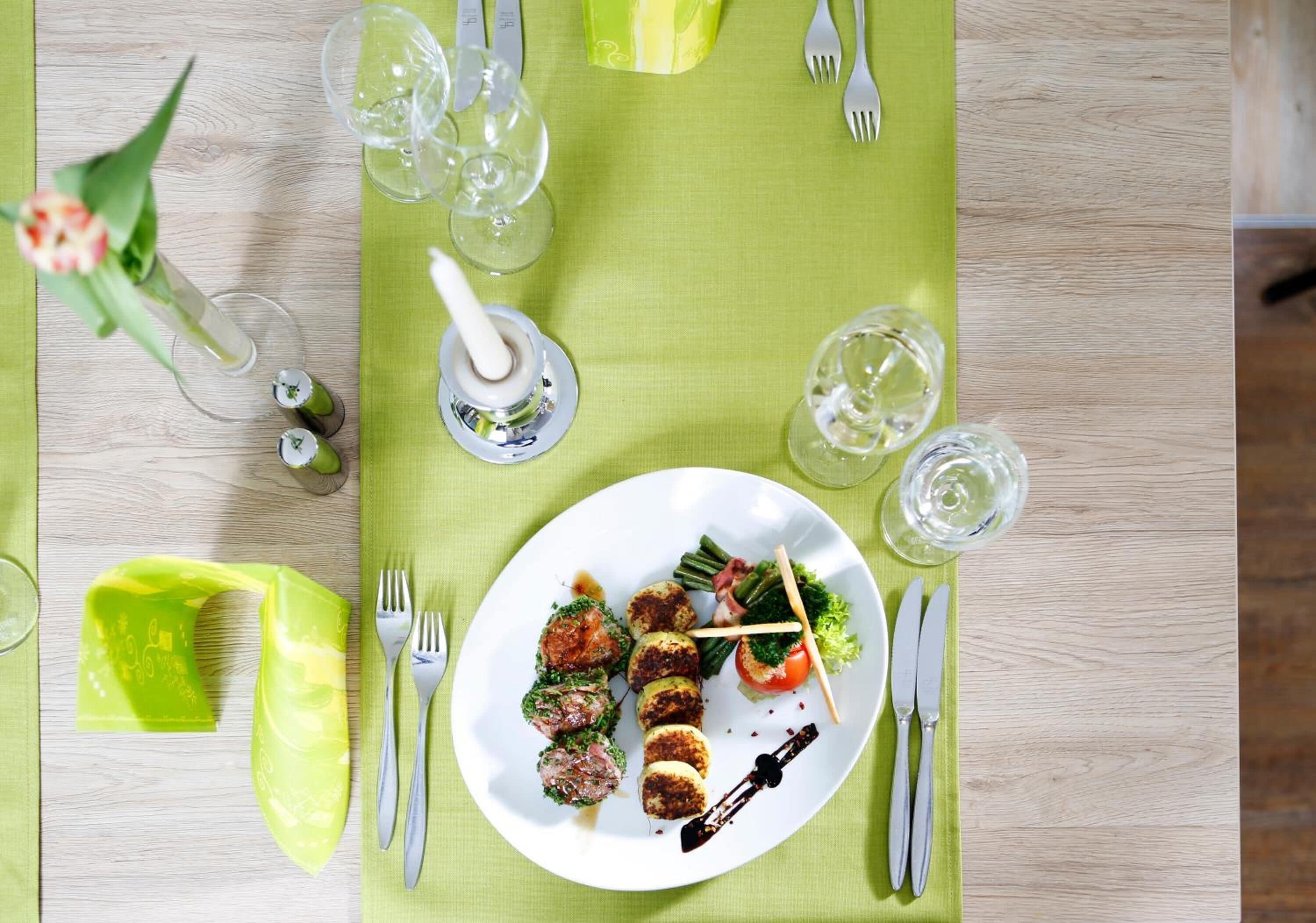 A dining table set with a plate of food, cutlery, and glasses.