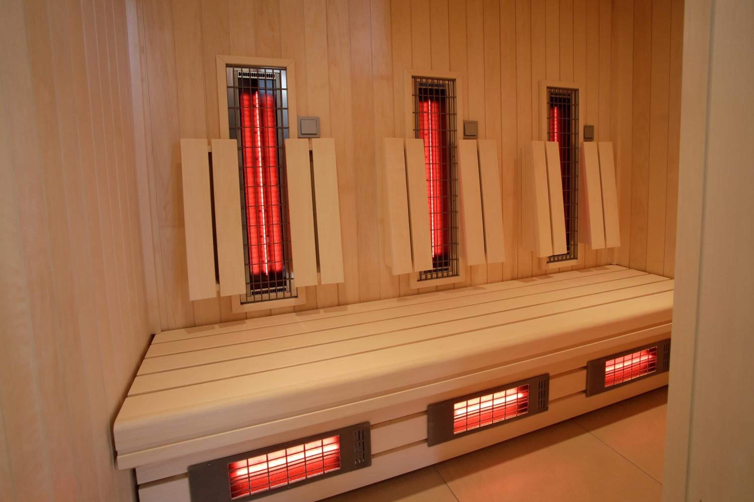 A sauna room with wooden walls, a bench, and infrared heating panels.