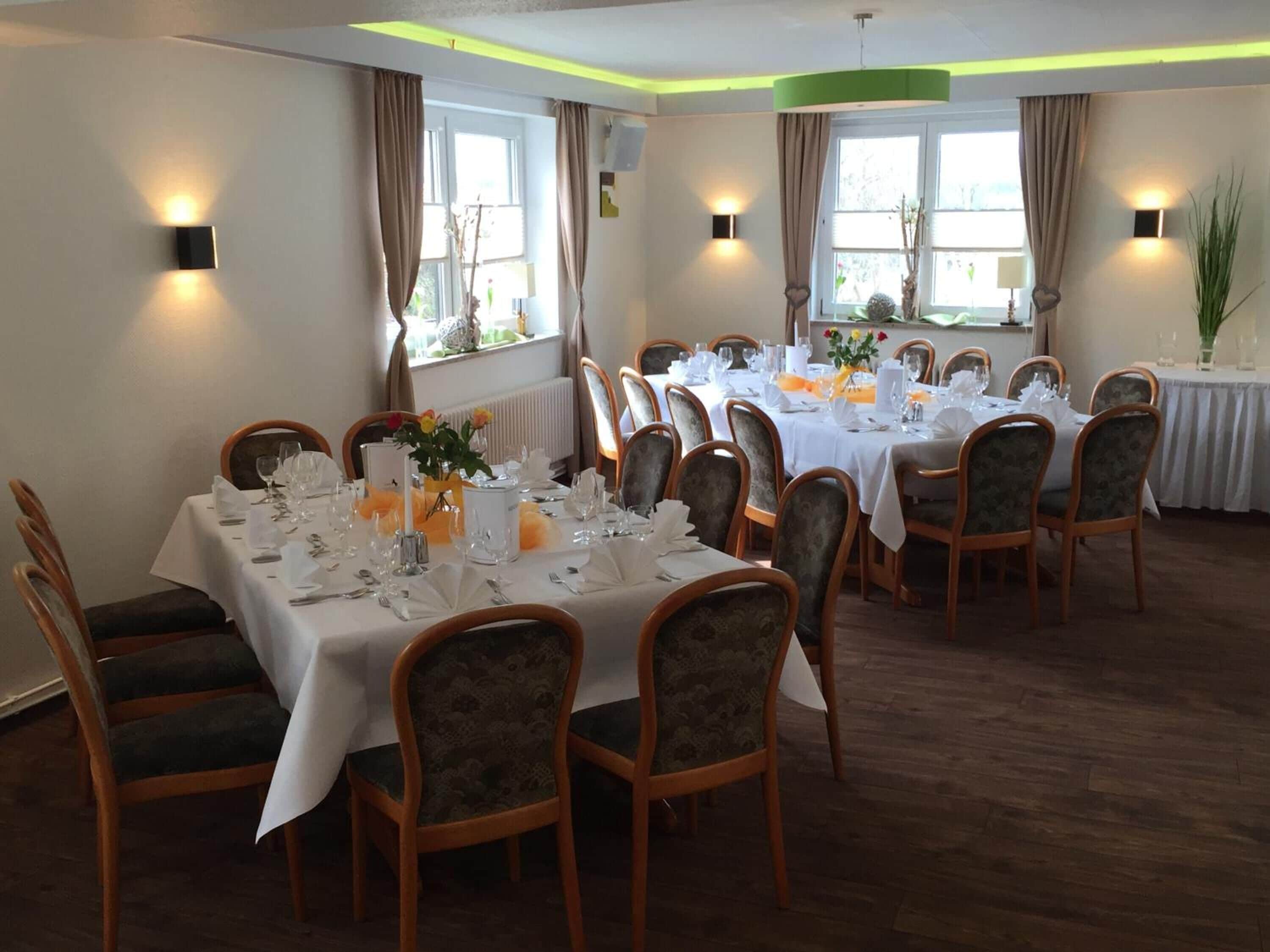 A dining area with tables set for a meal, chairs, and decorative elements like flowers and candles.