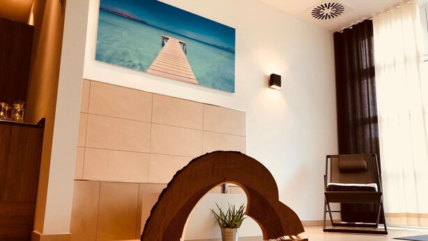 Een moderne lobby met een houten sculptuur, een schilderij van een pier en een potplant.