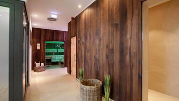 Un pasillo con paredes de madera, una cesta de mimbre y una habitación iluminada en verde al fondo.