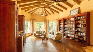 Ein geräumiges Wohnzimmer mit Holzboden, Deckenventilator und einer großen Bücherwand voller Bücher.