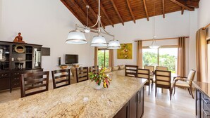 A spacious kitchen with a granite countertop, wooden chairs, and a ceiling with exposed beams. - Grand Laguna Beach Properties by Calisto Stays (Sosúa)