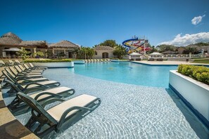 A swimming pool with lounge chairs, a water slide, and thatched-roof buildings. - Ocean Village 93 (Sosúa)