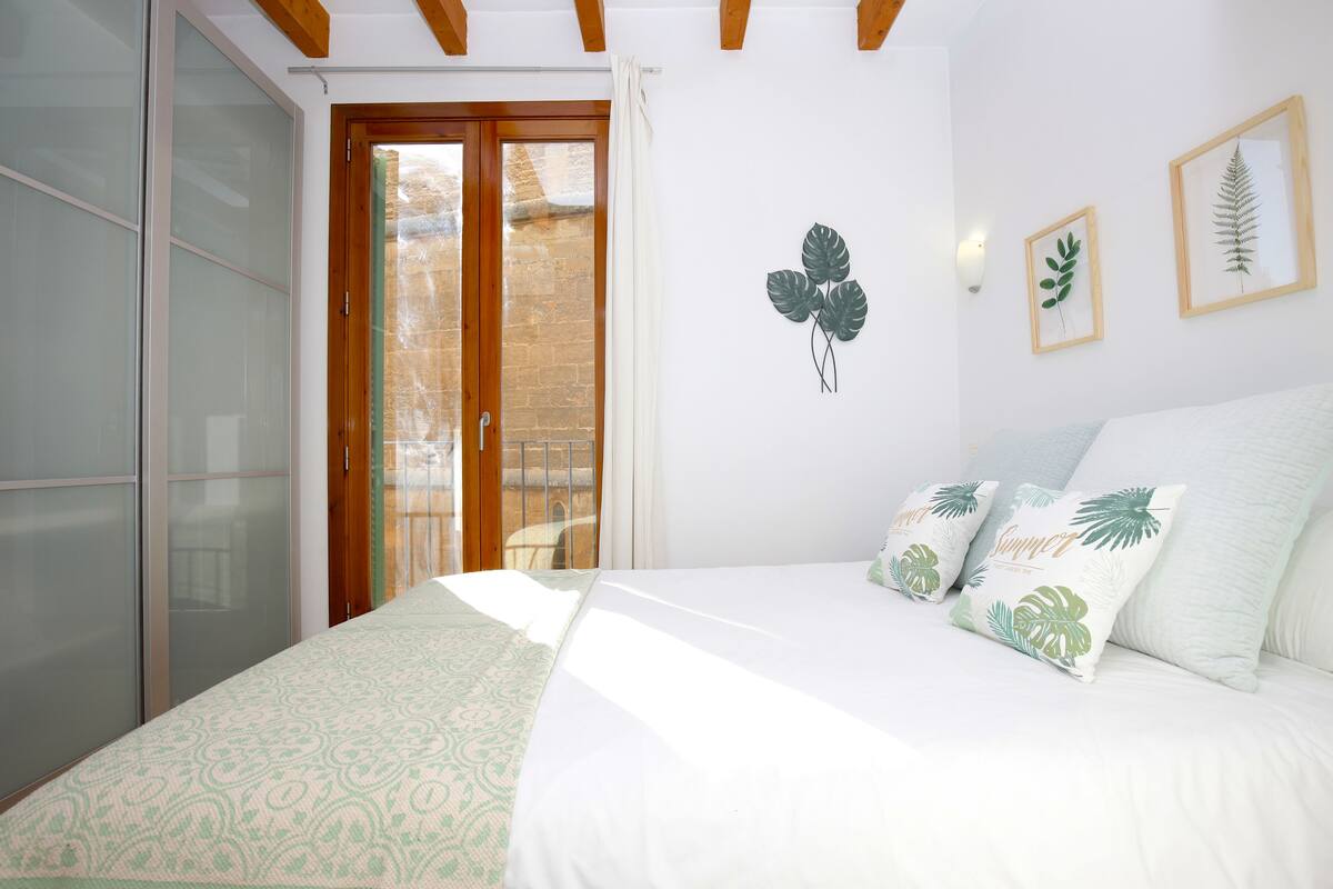 Ein Schlafzimmer mit einem Bett, einer Schiebetür und zwei gerahmten Blättern an der Wand.