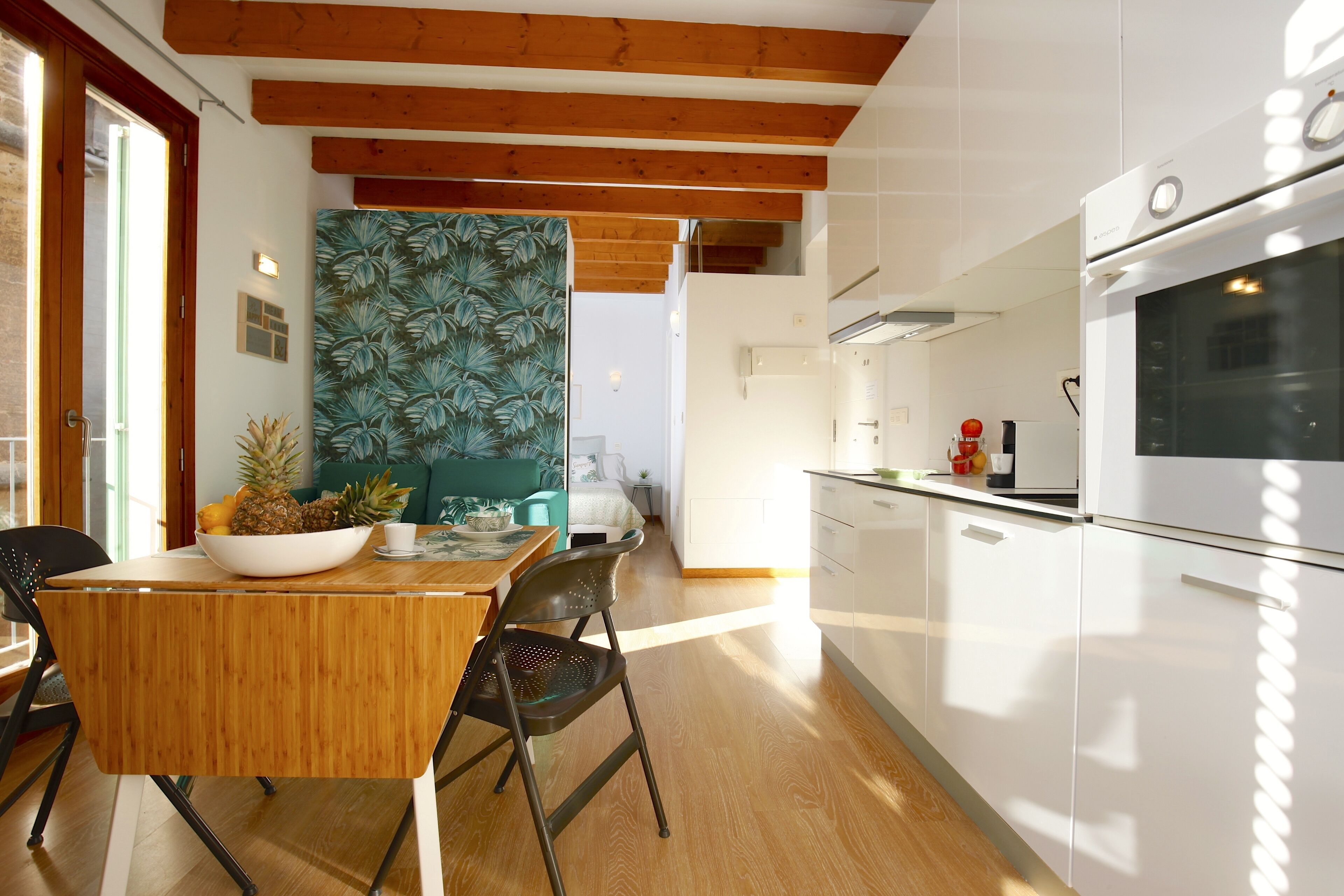 Eine moderne Küche mit Holzbalken, weißen Schränken und einem großen Backofen.