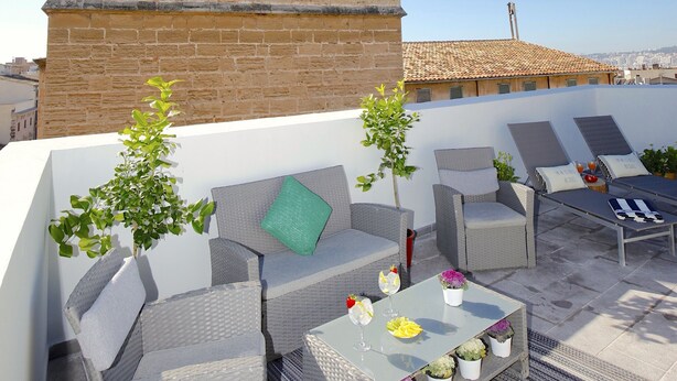 A rooftop terrace with outdoor seating, a stone tower, and a clear sky. - Sant Miquel Homes - Turismo de Interior (Palma de Mallorca)