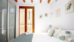 A bedroom with a bed, pillows, a blanket, and a view of the outside. - Sant Miquel Homes - Turismo de Interior (Palma de Mallorca)