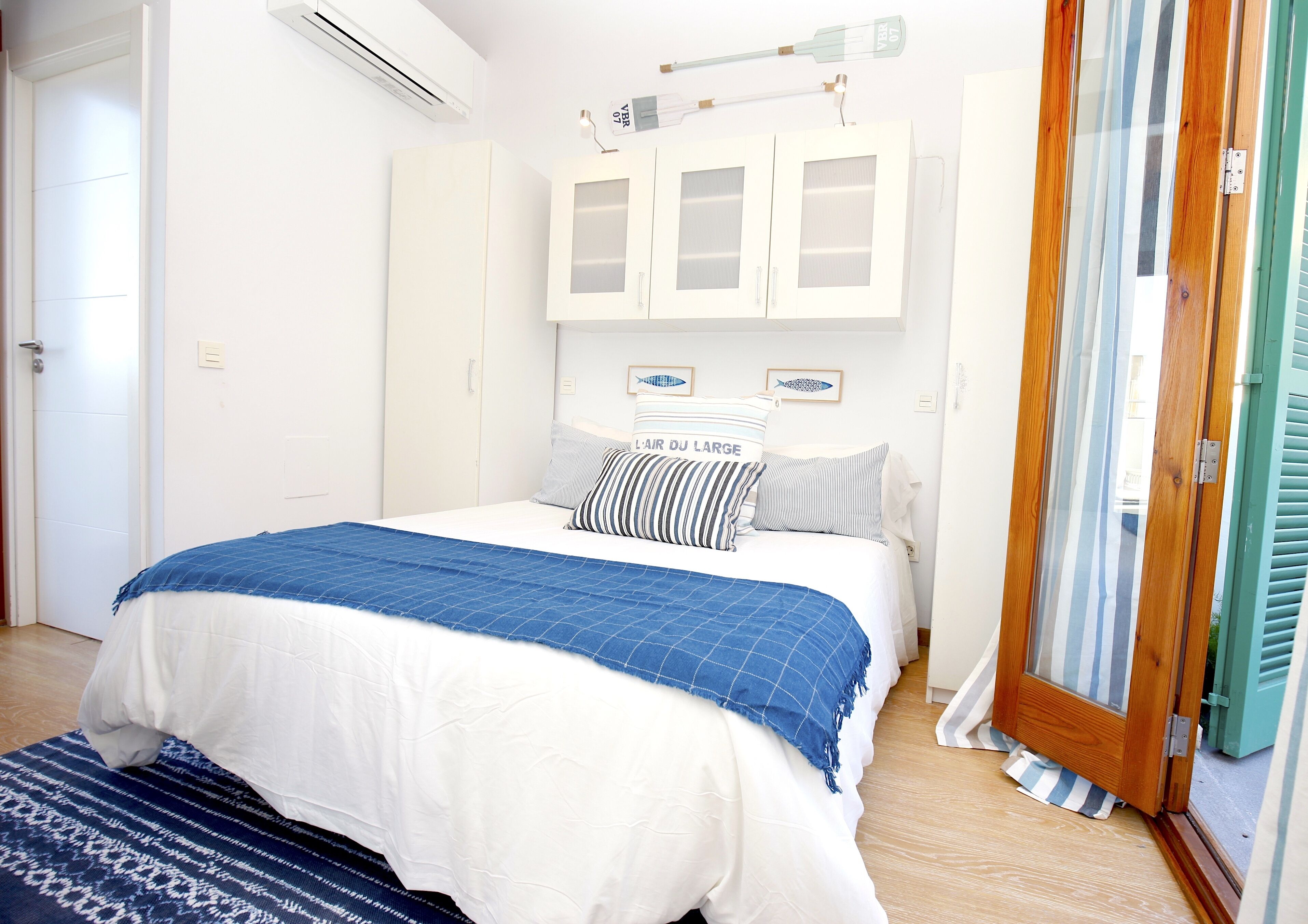 A bedroom with a bed, white wardrobe, and a wooden door with a striped curtain.