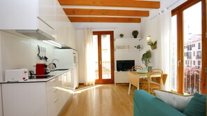 A compact kitchen with white cabinets, a red toaster, and a wooden dining table with chairs. - Sant Miquel Homes - Turismo de Interior (Palma de Mallorca)