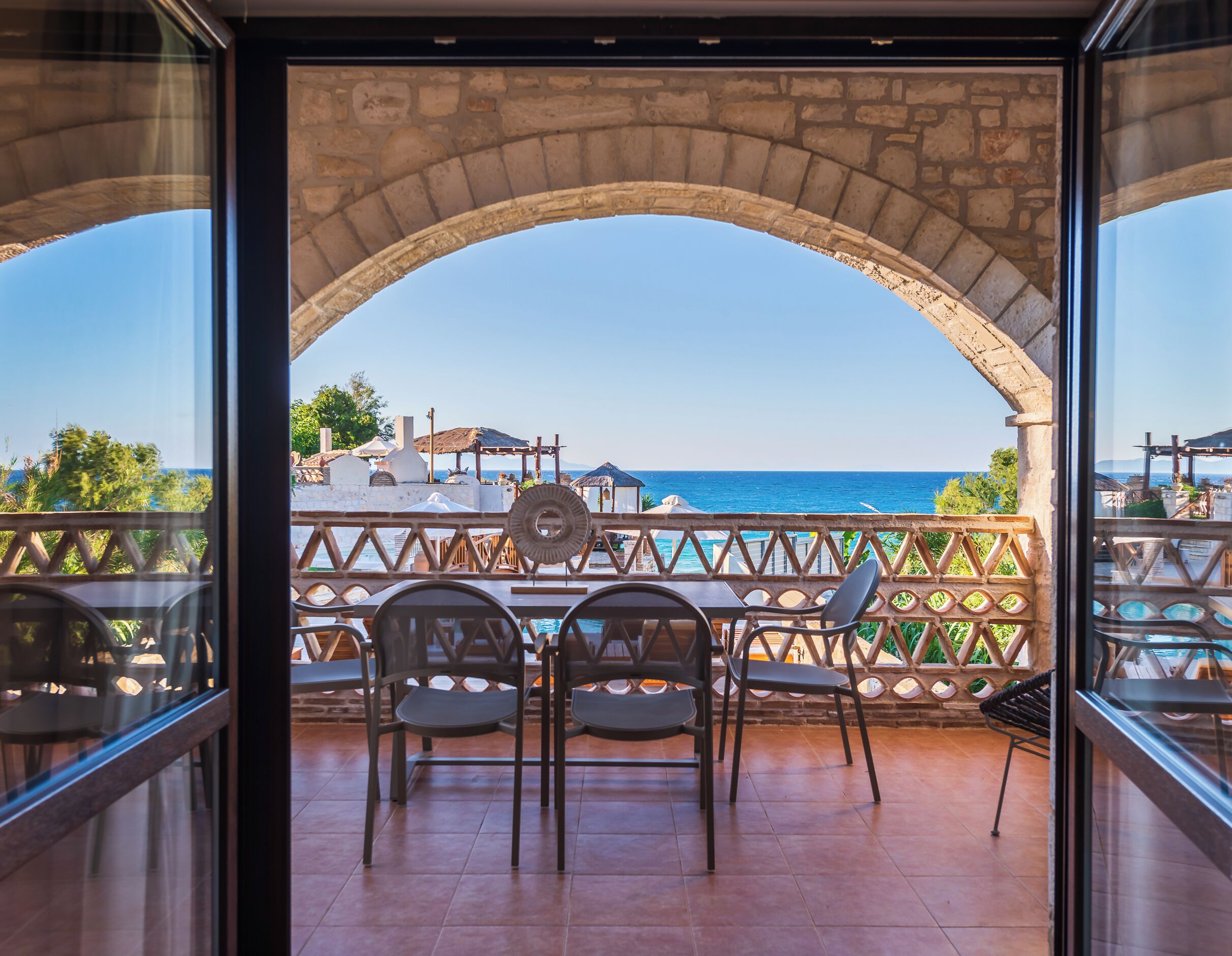 Una terraza con un arco de piedra, con vistas a una piscina y al mar.
