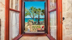 Eine geöffnete Tür, die zu einem Balkon mit Blick auf das Meer und Palmen führt.