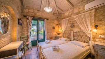Un dormitorio con dos camas, un escritorio y una silla. Tiene una ventana con cortinas, un espejo y un aire acondicionado de pared.