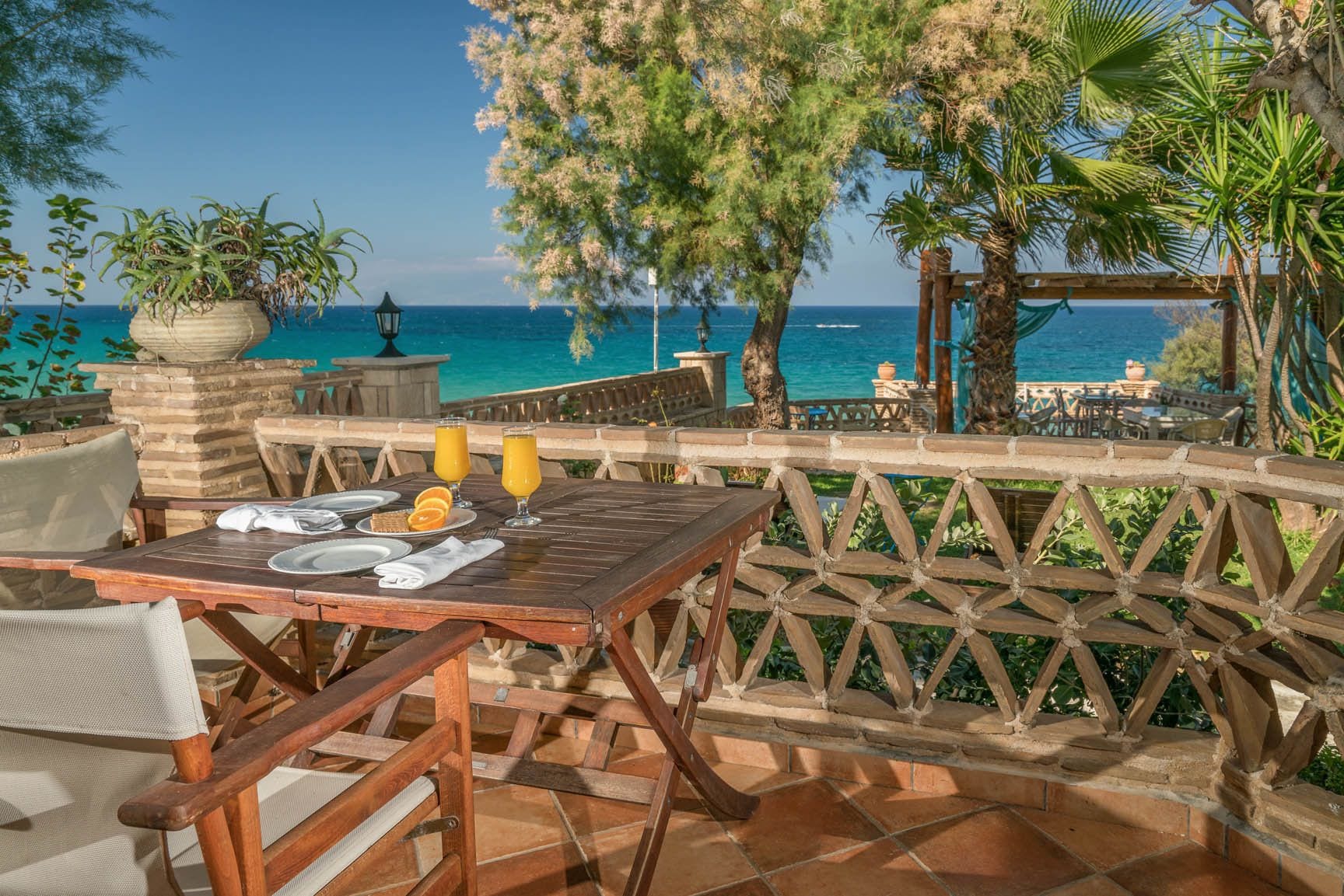 Un espace de restauration en plein air avec une table dressée pour deux personnes, offrant une vue sur la côte.