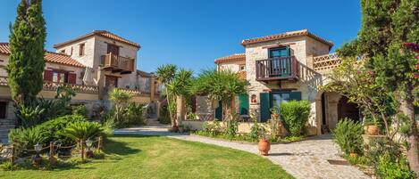 A courtyard with stone buildings, potted plants, and a clear blue sky.