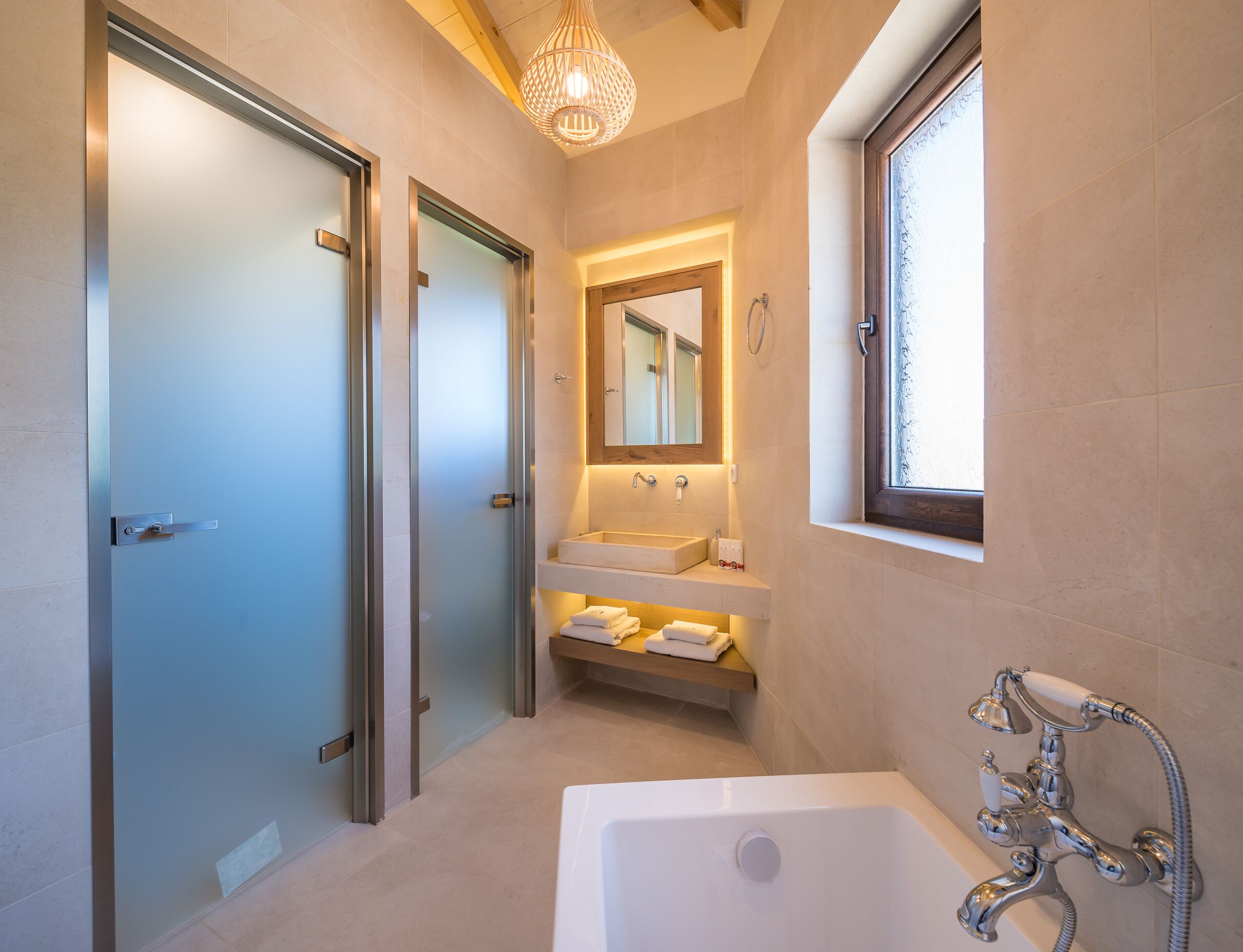 A modern bathroom with a glass shower door, a built-in sink, a vanity with a mirror, and a bathtub.