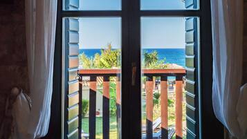 Vista a través de una ventana con balcón, mostrando un cielo despejado y una vista distante del mar.