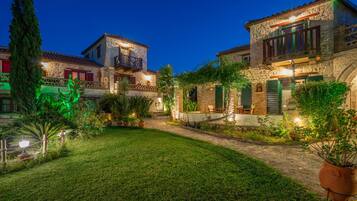 A stone building with a balcony, surrounded by a well-maintained garden and potted plants.