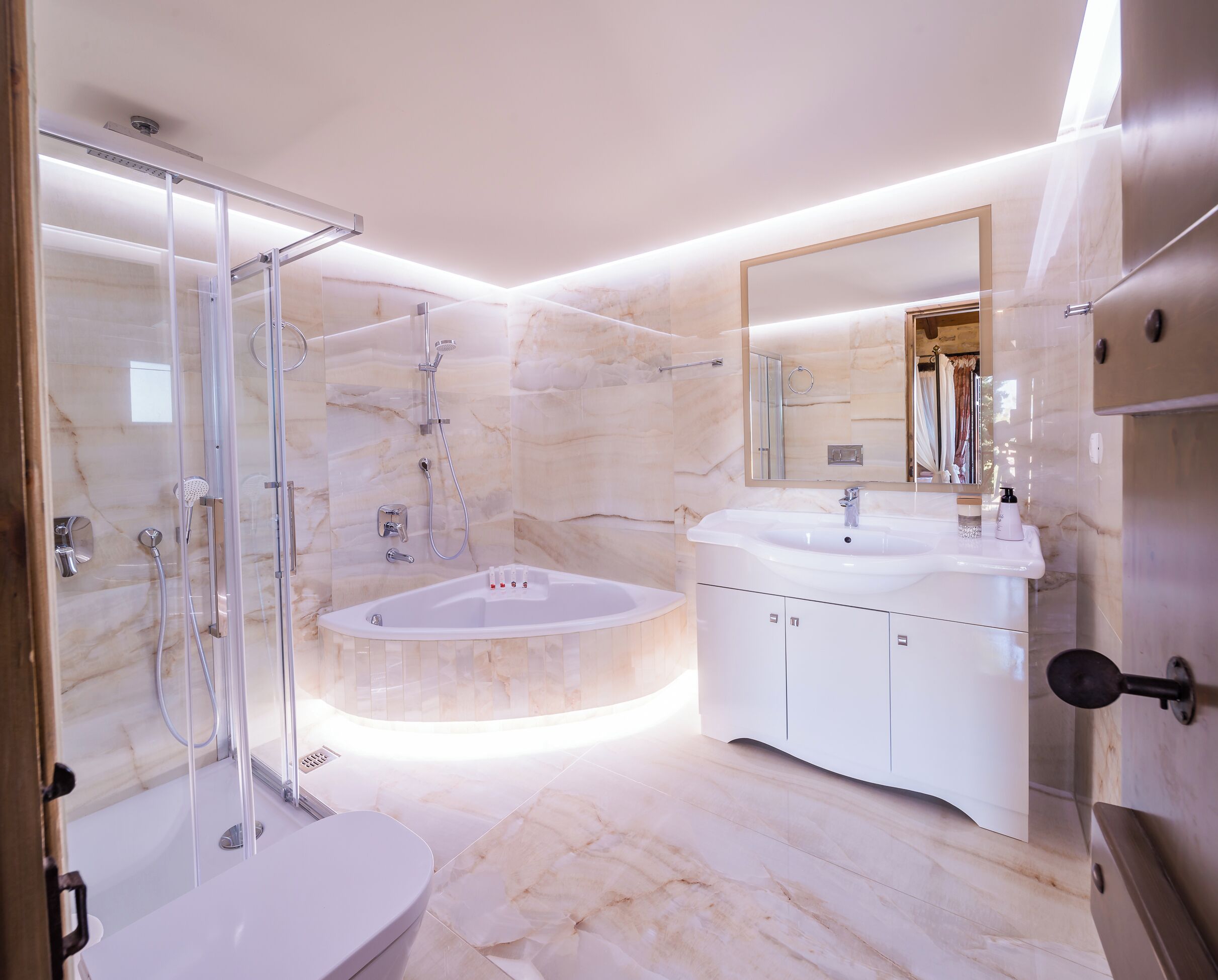 Een moderne badkamer met een douchecabine van glas, een vrijstaand bad en een wastafel met spiegel.