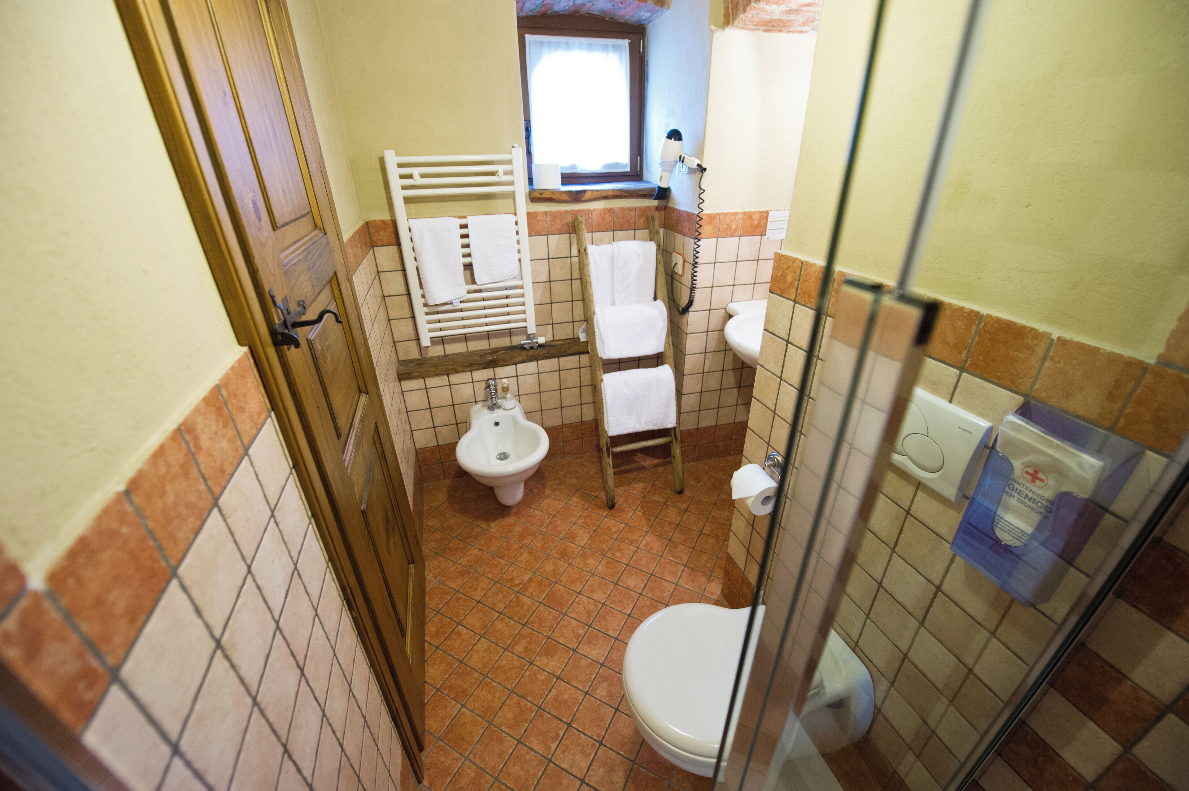 A bathroom with a toilet, bidet, and a window.