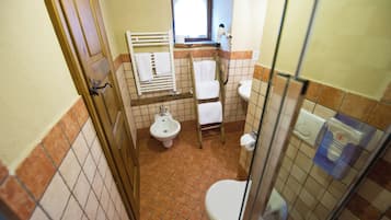 A bathroom with a toilet, bidet, and a window.