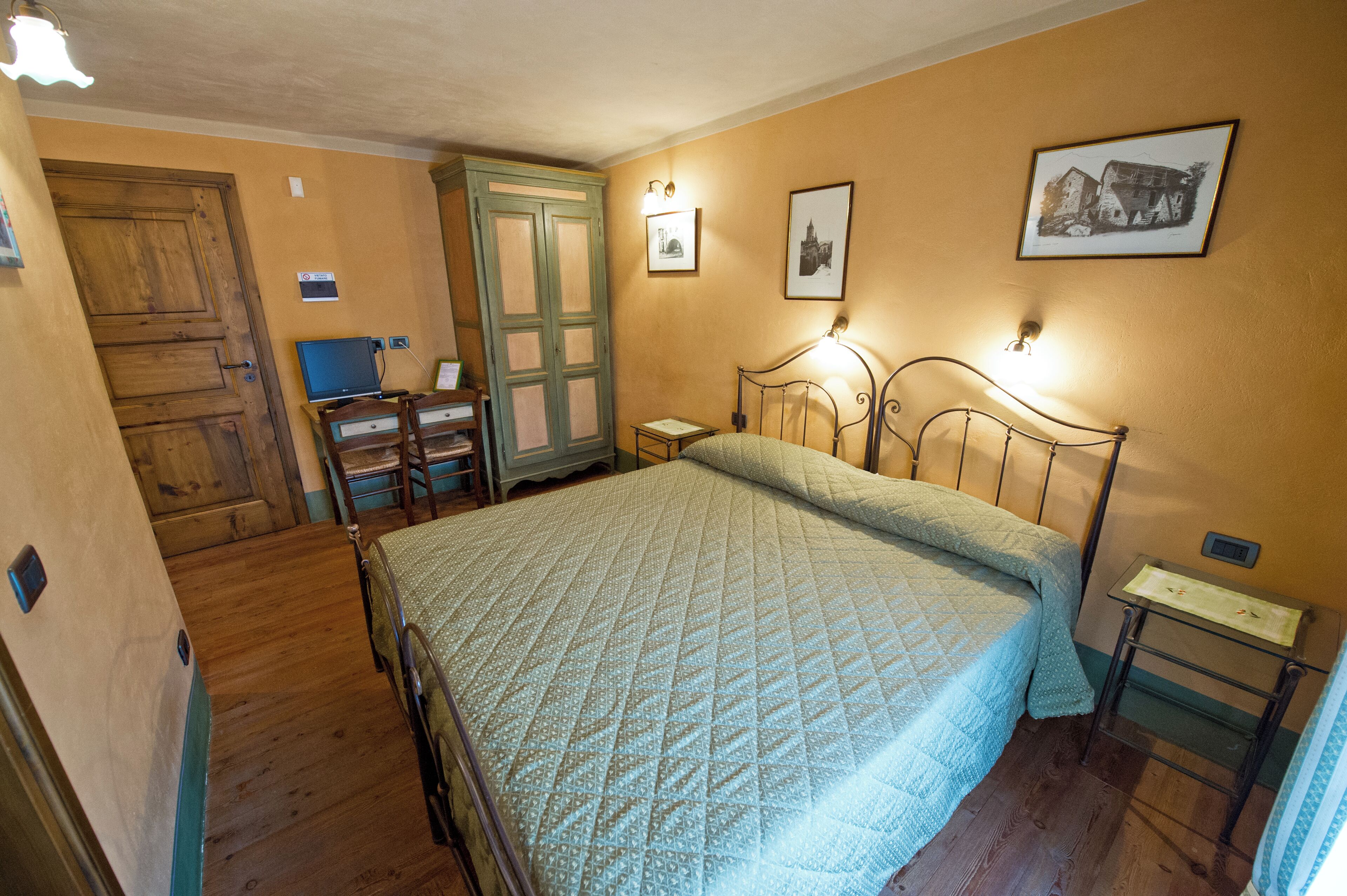 A bedroom with a bed, wooden wardrobe, and a desk with a chair.