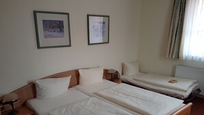 A hotel room with two single beds, a wooden headboard, a bedside table with a lamp, and two framed pictures on the wall. - Ratskeller Nörten (Norten-Hardenberg)