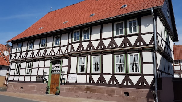 A traditional half-timbered building with a red-tiled roof, multiple windows, and a sign indicating it is a hotel and restaurant. - Ratskeller Nörten (Norten-Hardenberg)