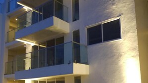 Un edificio de varios pisos con balcones, ventanas amplias y un exterior bien iluminado.