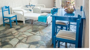 A room with a stone floor, white furniture, a blue table, and a view of the sea. - Phoenix Beachside Condos (Velo-Vocha)
