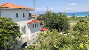 A white building with a red-tiled roof, surrounded by lush greenery and a view of the sea. - Phoenix Beachside Condos (Velo-Vocha)