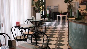 Un vestíbulo de hotel con piso a cuadros, una zona de bar central y arreglos de asientos.