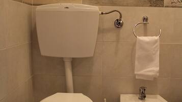 Un bagno con un water, un bidet e un porta asciugamani.