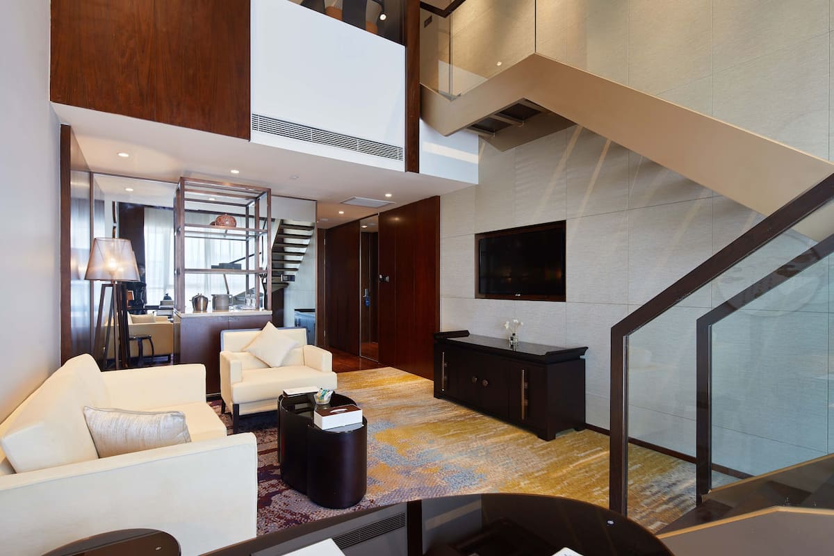 A spacious living area with a high ceiling, a staircase, and a modern design.