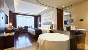 Una habitación de hotel moderna con una cama grande, un baño separado con bañera y un escritorio con silla.