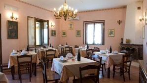 A dining area with multiple tables set for guests, a chandelier, and framed artwork on the walls. - Agriturismo Tempa del Niglio (Ascea)