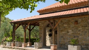 A stone building with a tiled roof and wooden beams, surrounded by potted plants and greenery. - Agriturismo Tempa del Niglio (Ascea)