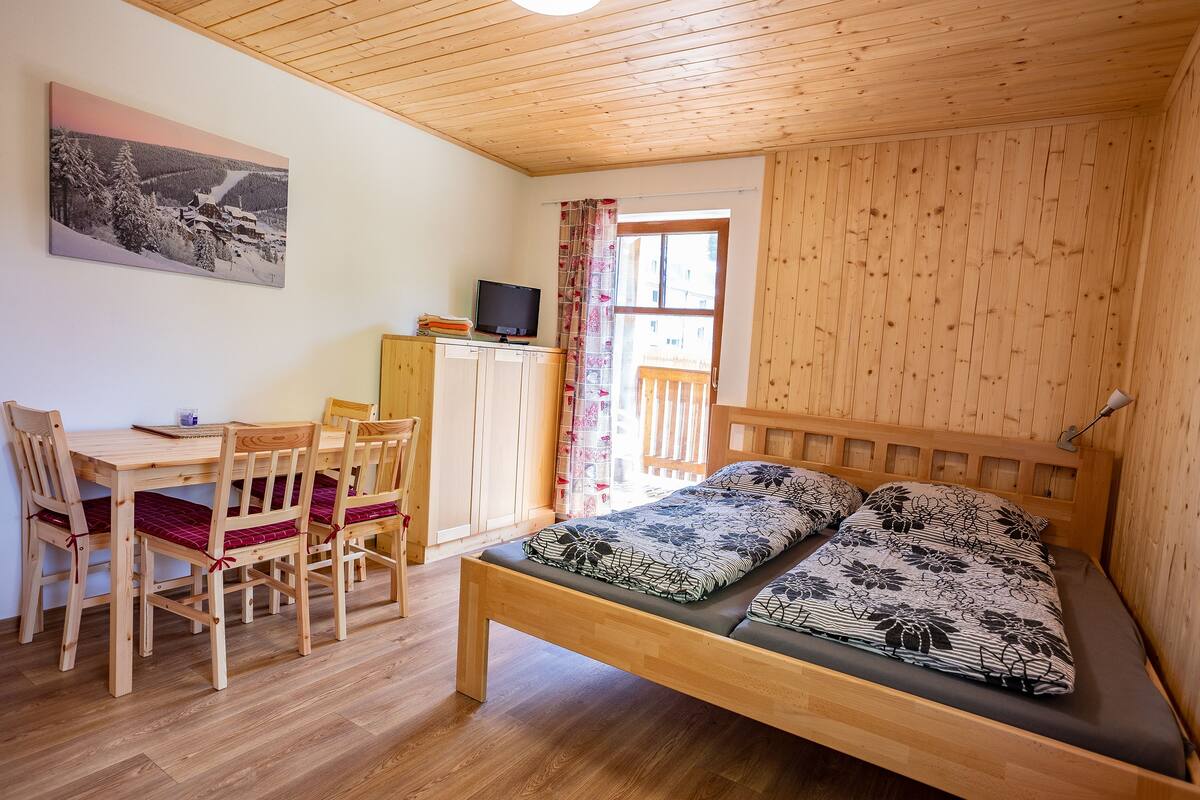 L’intérieur d’un chalet en bois, avec un lit, un bureau et des chaises.