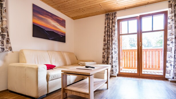 Un salon avec un canapé, une table basse et une grande fenêtre avec des rideaux.