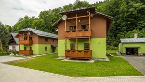 Une cabane en bois à deux étages, dotée d’un balcon et entourée d’une végétation luxuriante.