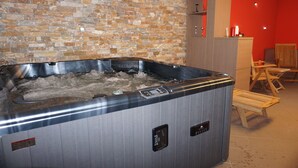 Un espace spa moderne avec un mur en pierre, un jacuzzi et des meubles en bois.