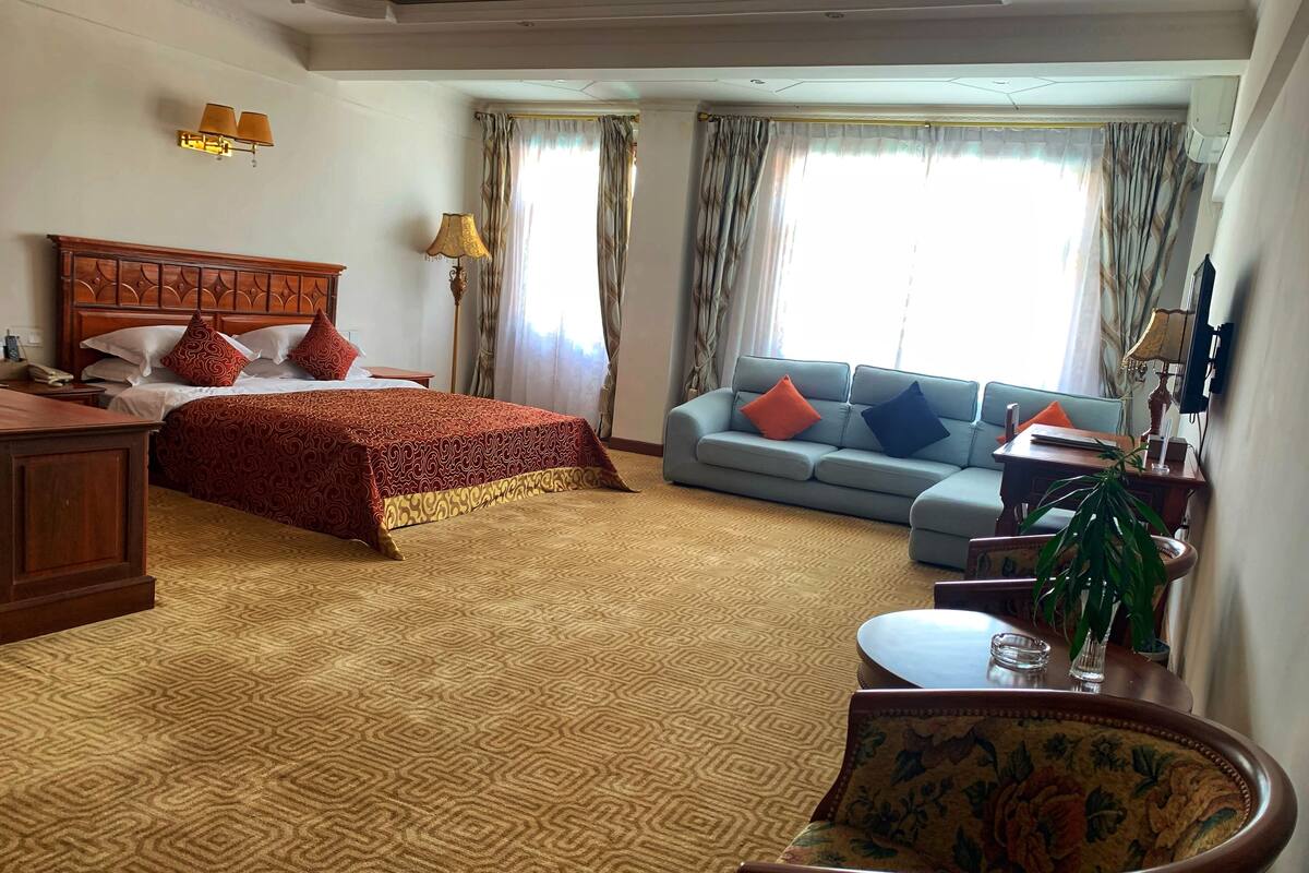 A hotel room with a large bed, a sofa, a desk, and a chair.