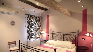 A bedroom with a bed, a chair, a small table, a window with a curtain, and a radiator. - B&B Ciliegio Felice (Argenta)