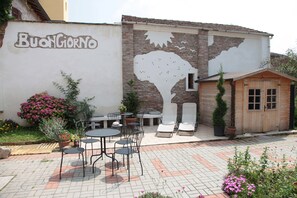 A courtyard with outdoor seating, a wooden structure, and a wall with a mural. - B&B Ciliegio Felice (Argenta)