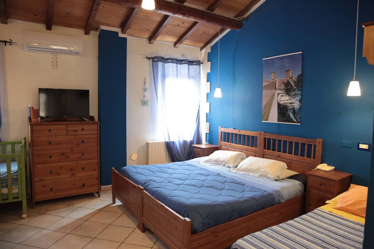 A bedroom with a wooden bed, a television, a dresser, and a poster on the wall.