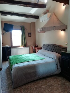 A bedroom with a bed, a desk, a chair, an air conditioning unit, and a television. - B&B Ciliegio Felice (Argenta)